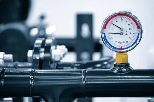 Photo of Industrial  concept. equipment of the boiler-house, - valves, tubes, pressure gauges, thermometer. Close up of manometer, pipe, flow meter, water pumps and valves of heating system in a boiler room.