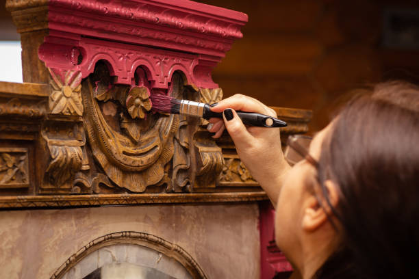 mulher colorindo enferrujado enferrujado ornamentos de madeira aparador buffet na cor rosa com pincel grande. nova vida de coisas antigas. restauração de peças de mobiliário antigo - patination - fotografias e filmes do acervo