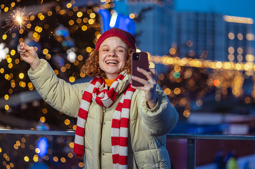Shot of a smiling redhead woman holding sparklers and taking a selfie