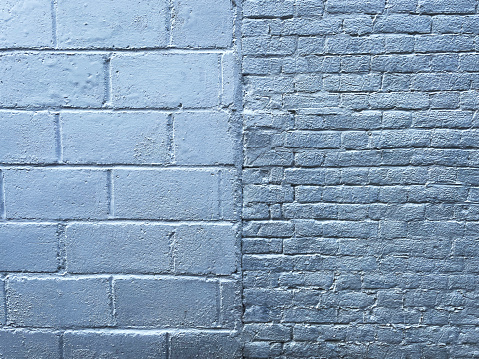 Brick wall painted with blue dark paint pastel calm tone texture background. Brickwork and stonework flooring interior rock old pattern clean concrete grid uneven bricks design stack backdrop.