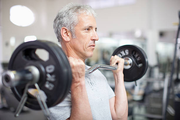 retrato de hombre sonriente sosteniendo barra para pesas en el gimnasio - barbell exercising sport gym fotografías e imágenes de stock