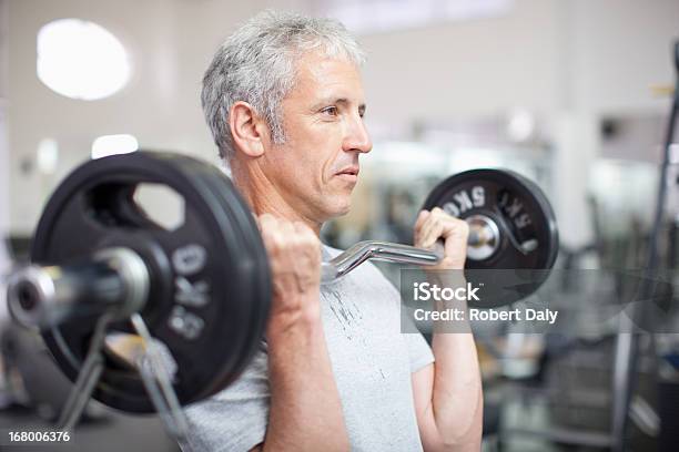 Portrait Of Smiling Man Holding Barbell In Gymnasium Stock Photo - Download Image Now