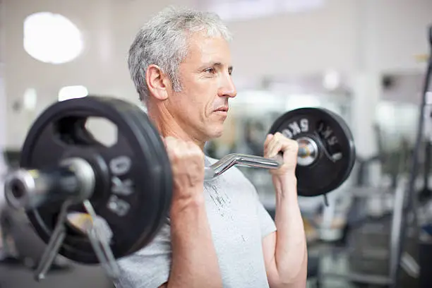 Photo of Portrait of smiling man holding barbell in gymnasium