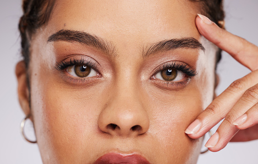 Studio portrait of beautiful young girl with cat-eye makeup and bright lip gloss