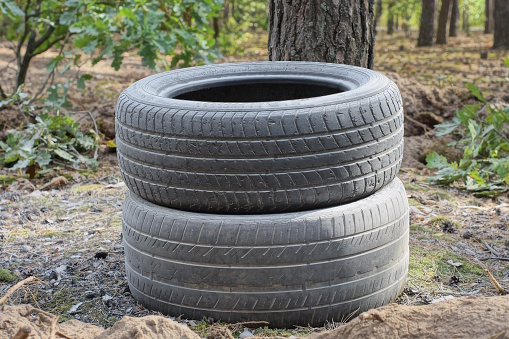 two large black old car tires lie on the gray ground on the street