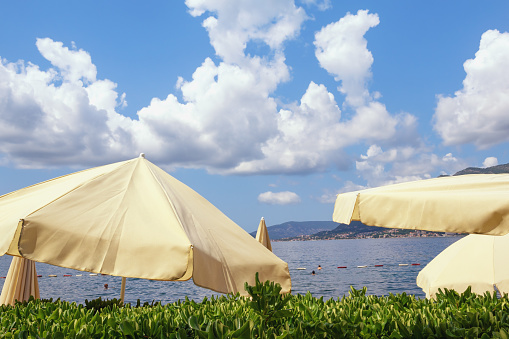 Summer beach vacation. Beautiful sunny Mediterranean landscape. Sun umbrellas on coast of Bay of Kotor. Montenegro, Tivat