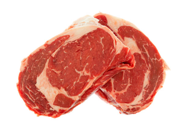 Overhead view of two fresh ribeye steaks isolated on a white background.