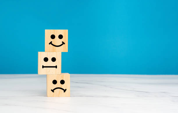 istock Satisfaction concept. Wooden cubes with stacked face icons over a table with a blue background 1680093668