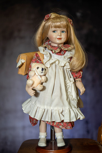 Realistic porcelain antique vintage doll or toy,  blonde hair and vintage dress.