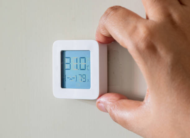 istock Woman hand fixing home hygrometer and temperature indicator electronic device. Uncomfortable indoor climate. 1680115512