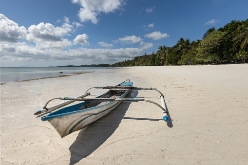 Small fishermens' canoe boat at the Ngurbloat white sand beach in Kei Islands, Maluku during bright sunny day and blue skies