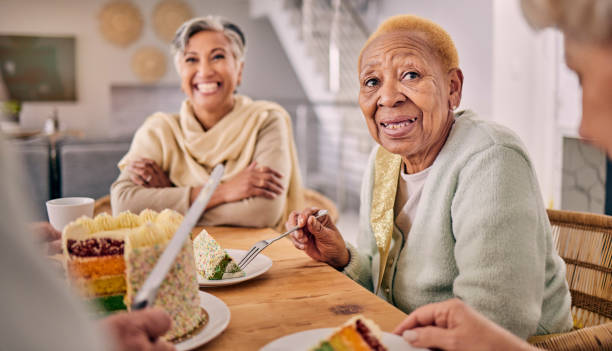 케이크, 대화, 다과회에서 식사하는 노인들, 집 식당에서 열리는 행사. 재미있고, 이야기하고, 노인 친구들이 양로원에서 함께 디저트나 달콤한 간식을 즐기고 있다. - senior adult nursing home eating home interior 뉴스 사진 이미지
