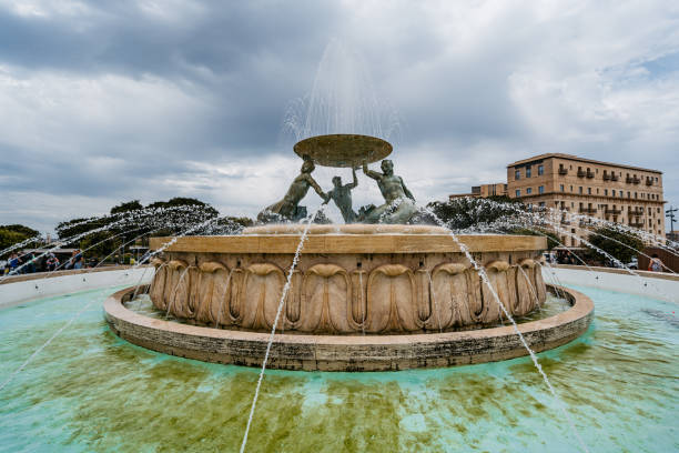 Vatican, March 09 -- A Bernini fountain in the majestic square of St Peter's Basilica, surrounded by the colonnade designed and built by Bernini himself in 1655. Characterized by giant columns and pilasters, the immense facade of San Pietro (118 meters wide and 48 high), was conceived by the architect Carlo Maderno to complete Michelangelo's previous project and built between 1608 and 1614. The Basilica of St. Peter's is the center of the Catholic religion, one of the most visited places in the world for its immense artistic and architectural treasures. In 1980 the historic center of Rome was declared a World Heritage Site by Unesco. Super wide angle image in high definition format.