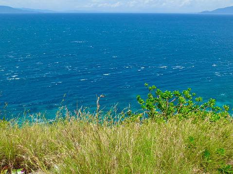 View of the sea surface from a steep cliff covered with grass.