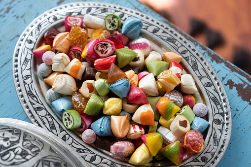 Top view of an assortment of multicolored candies, lollipops and jelly beans background. All the candies are at the borders of the image making a frame shape and leaving a useful copy space at the center of the image on a withe background.  Studio shot taken with Canon EOS 6D Mark II and Canon EF 24-105 mm f/4L