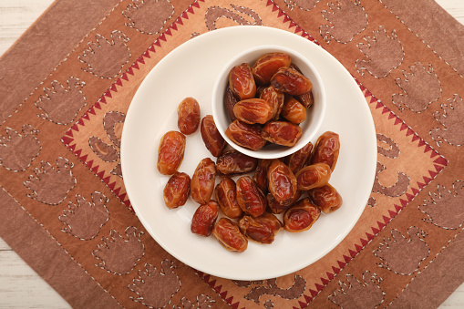 Dates fruit in a bowl on a wooden background. Top view.