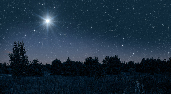 Bright star shines over the manger of christmas of Jesus Chris on blue starry sky