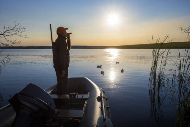 istock hunter standing it boat and blowing at hunter's whistle. duck hunter at sunrise. 1680206985