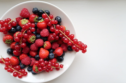 Berry mix in a white bowl, white background, strawberries, blueberries, raspberries, redcurrants mixed together, healthy snack, berries in a bowl, focus in details, sweet dessert, vitamin, good mix