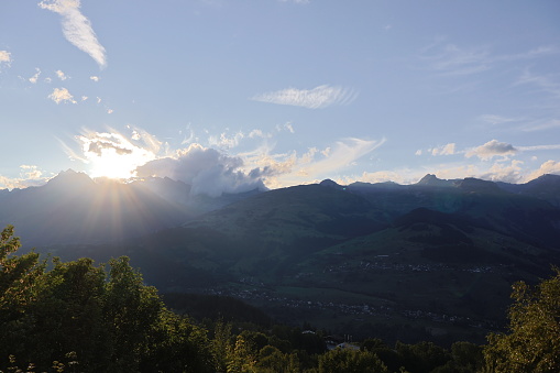 A picture of the sun creeping up from behind the Swiss mountains in the morning, with a beautiful clear sky.