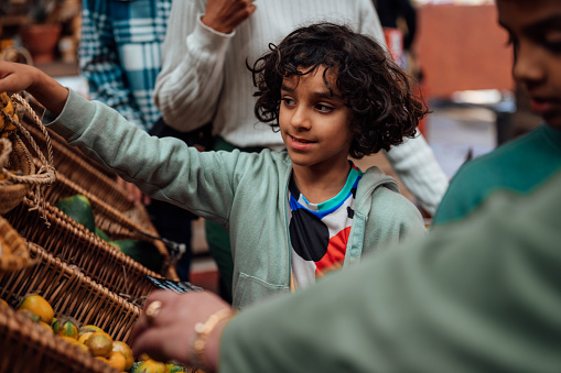 A young boy looks at fruit and veg on a market stall.