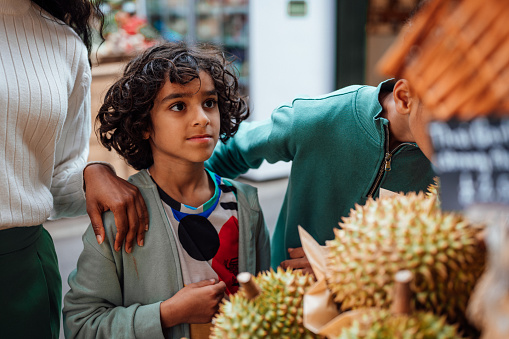 A young boy looks at fruit and veg on a market stall.