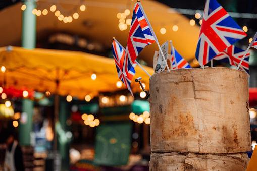 A wheel of cheese on a market stall with union jack flags stuck into it.