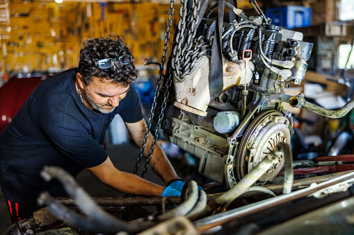 Car mechanic take the engine out from the car for disassebly