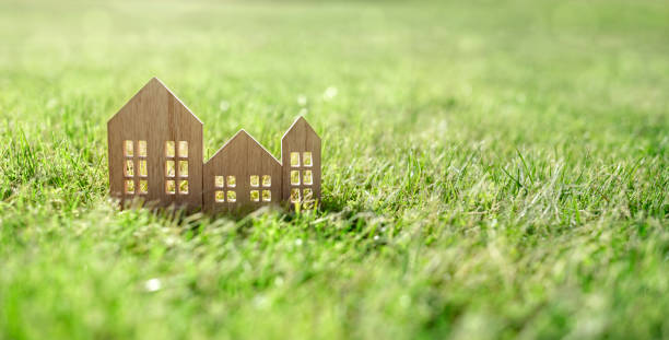 Eco wooden model house in empty field at sunset stock photo