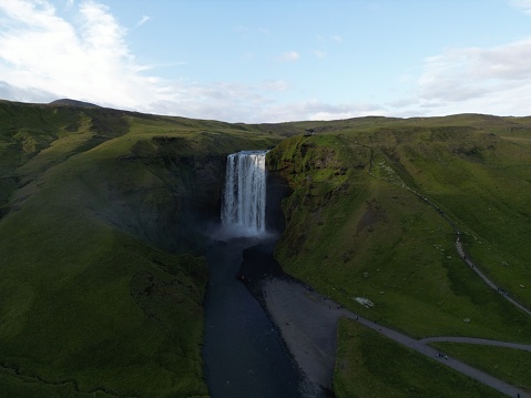 An aerial view of Skogafoss Waterfall in Iceland, framed by lush green moss-covered cliffs