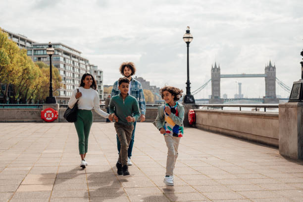 istock Two brothers run along a riverside as their parents walk behind them. 1680241726