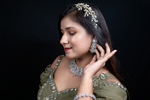 Close- up shot of Beautiful young female model showing earrings and Diamond necklace , Studio shot on black background.