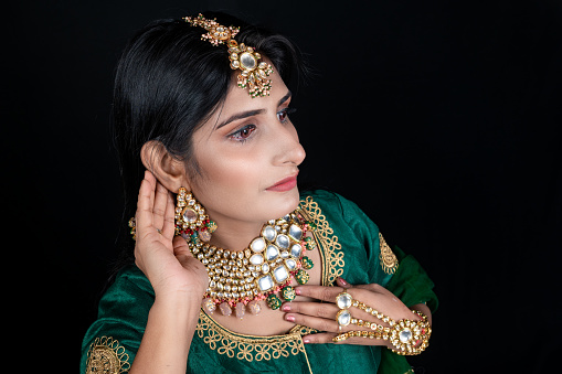 Closeup shot of young female model wearing Gold and diamond - gemstone wedding necklace with earing