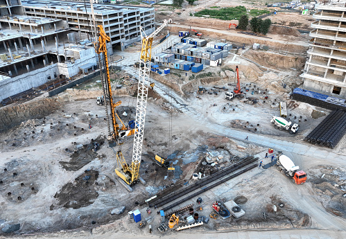 Deep foundation machine. Drilling rig and Pile driver at construction site. Pile driven into ground by vibrating hydraulic hammer. Cement mixer truck pouring concrete on building construction.