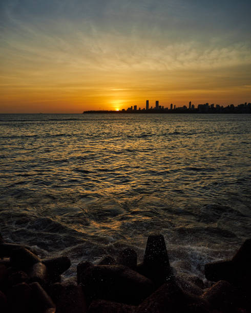 istock Sunset at Sea shore with rocks and Skyscrapers. 1680283662