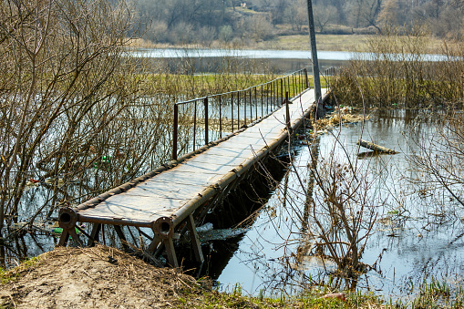 River bank in spring. A small pedestrian bridge across the river.