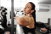 Fit woman doing squats with barbell in a gym