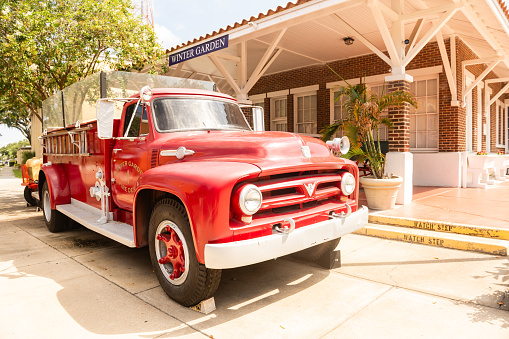 In Winter Garden, United States a stationary vintage red fire truck is displayed outside of the museum in the downtown area.