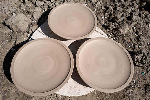 Three unglazed ceramic dishes on the ground in front of a clay kiln, Fez, Morocco.