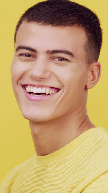Face, smile and portrait of a man in studio with a positive and carefree attitude. Happy young male student person from France with motivation, confidence and teeth or wellness on a yellow background