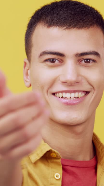 Come here, happy and portrait of a man in studio with a positive attitude. Headshot of excited young male student person from France with hand to welcome, smile and invitation on a yellow background