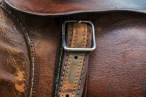 Horse saddle. Detail of the texture, stitching, buckle and leather belt.