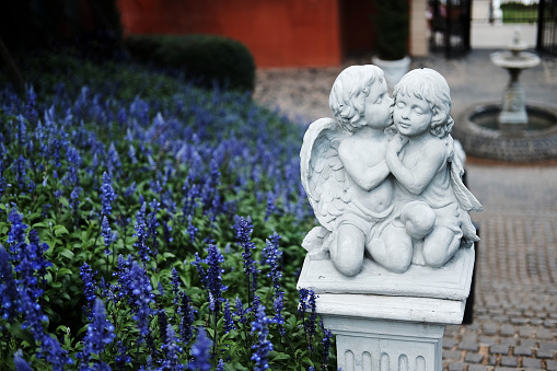 White children couple and lover angle marble statue of roman decorated in the flowers garden