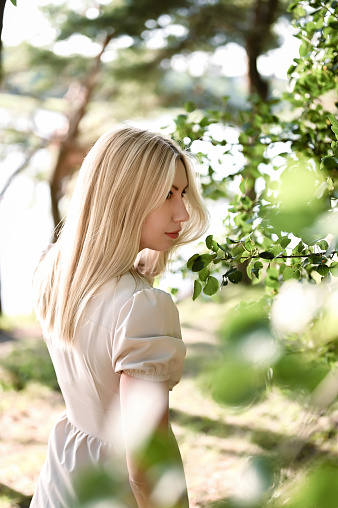 side view portrait of a young woman with natural beauty in a green forest.