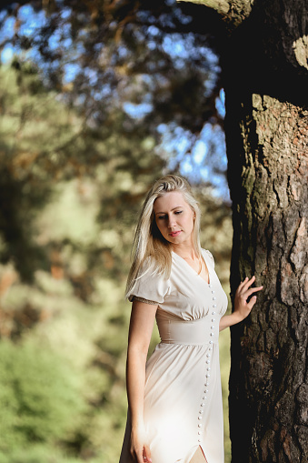 Portrait of a young woman in the forest near the tree trunk.