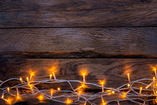 Empty rustic wooden table with Christmas lights at the bottom border