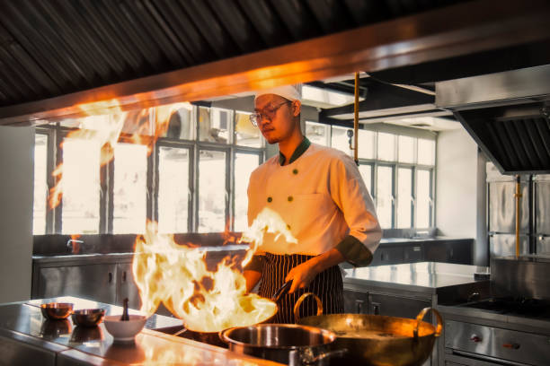 istock hef in the professional kitchen with a frying pan and a fire. Chef's hands hold iron Pan 1680473854
