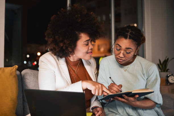 istock Night, working and writing ideas on notebook, laptop or intern with project, research and teamwork with African women. Employees, together and conversation for collaboration or brainstorming startup 1680475147