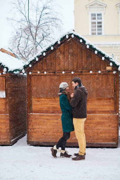 Young loving couple dressed in plaid scarves walk at the old city in winter