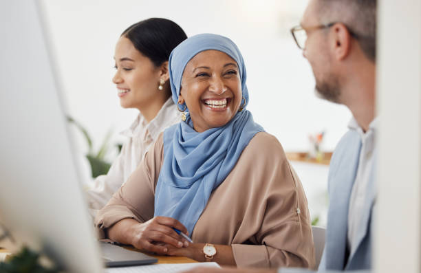 istock Happy, teamwork and business people in office for training, advice and collaboration while working on a computer. Smile, laugh and Muslim senior woman mentor laugh with work friend while planning 1680488234